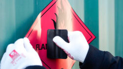 A person applying a hazard label to an uneven surface