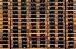 Numerous wooden pallets are stacked on top of each other.