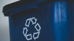 A blue rubbish bin with a white recycling symbol