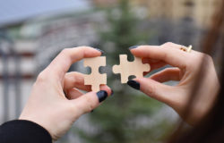 A person joining two pieces of a puzzle.